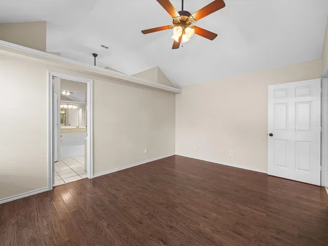 an empty room with wooden floor closet and windows