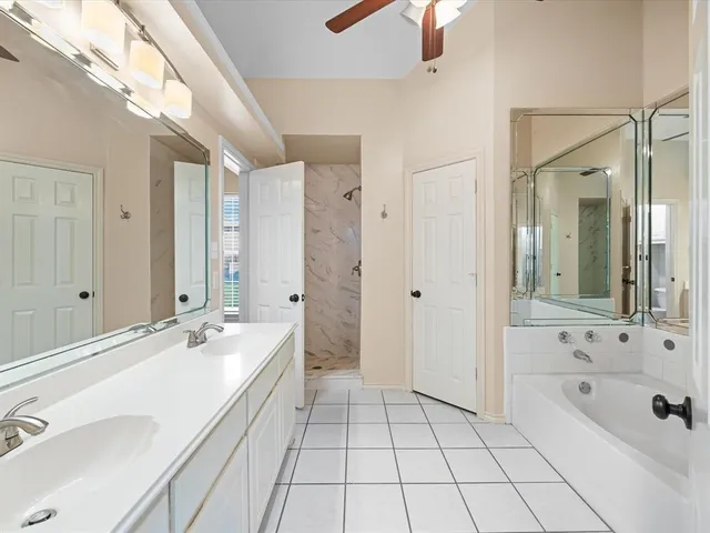 a spacious bathroom with a tub sink and mirror