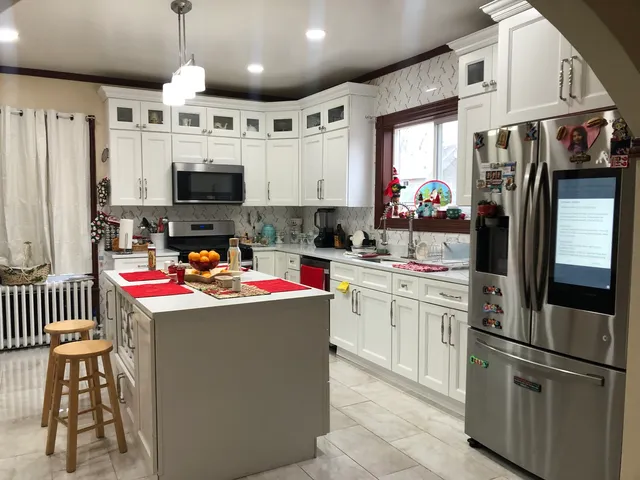 a kitchen with kitchen island a sink stainless steel appliances and white cabinets