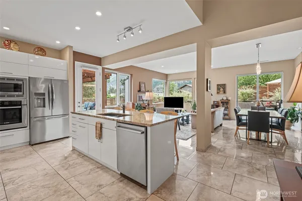 a kitchen with stainless steel appliances kitchen island granite countertop a table and chairs in it
