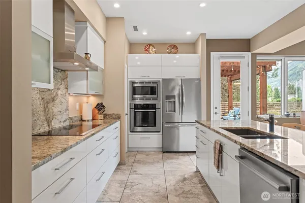 a large white kitchen with granite countertop a sink and cabinets