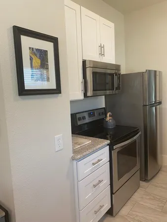 a kitchen with granite countertop white cabinets and stainless steel appliances
