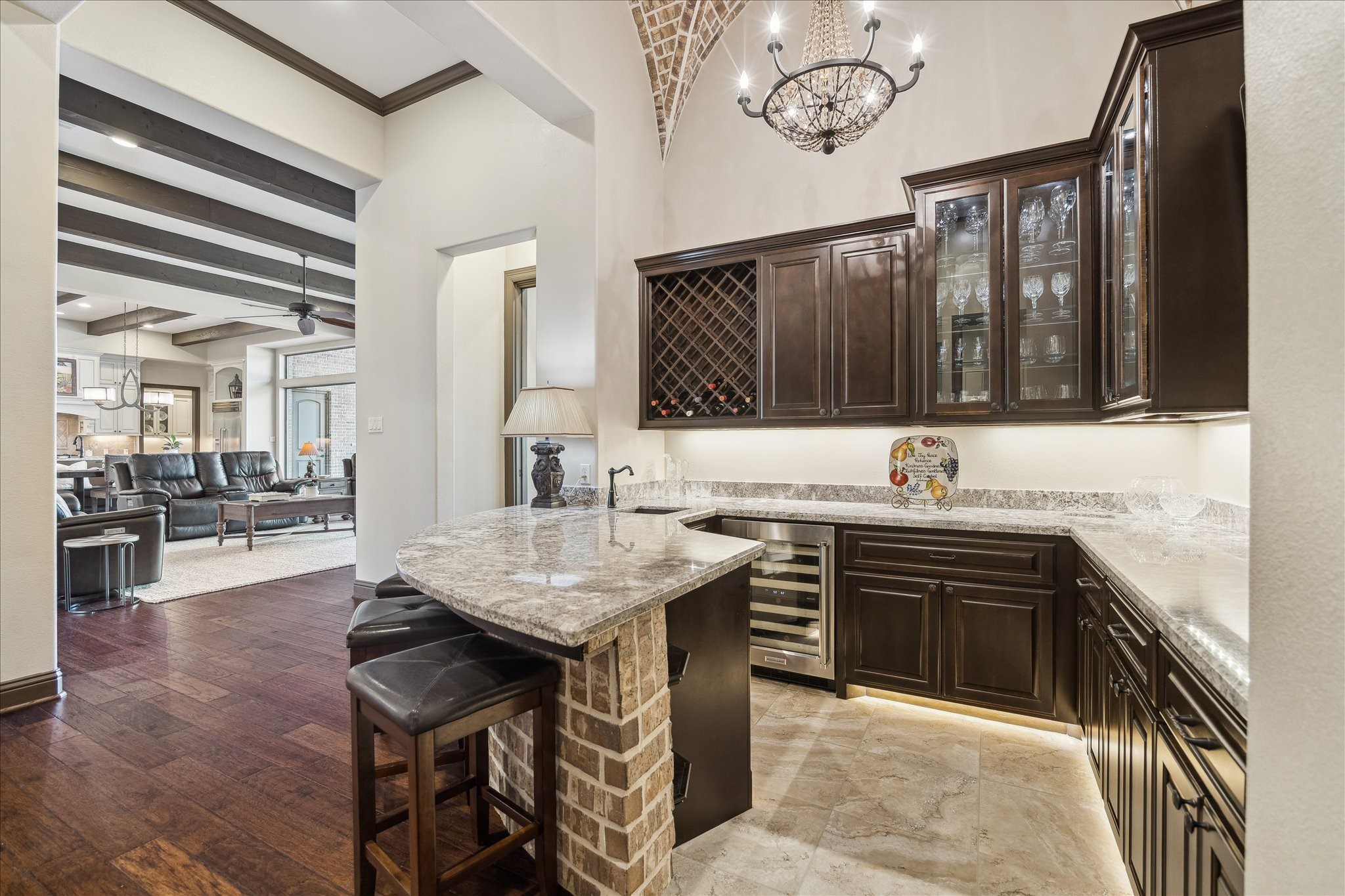 11 Willowcreek Ranch Road Tomball, TX 77377 - Photo 37 of 49 The bar is outfitted with a sink, richly stained cabinetry, display cabinetry, wine racks, granite counters, an icemaker and a wine refrigerator. A charming chandelier descends from its brick groin vault ceiling, creating a delightful area to visit with guests and entertain!