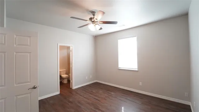 an empty room with wooden floor chandelier fan and windows