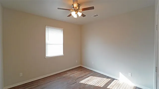 an empty room with windows and fan