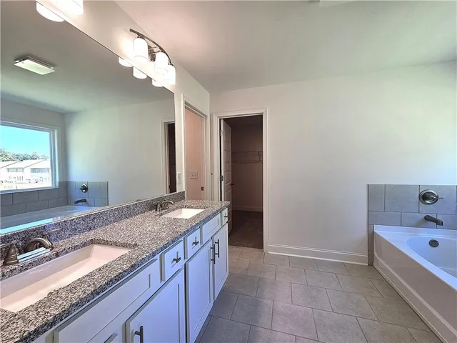 a bathroom with a granite countertop sink a toilet a mirror and bathtub