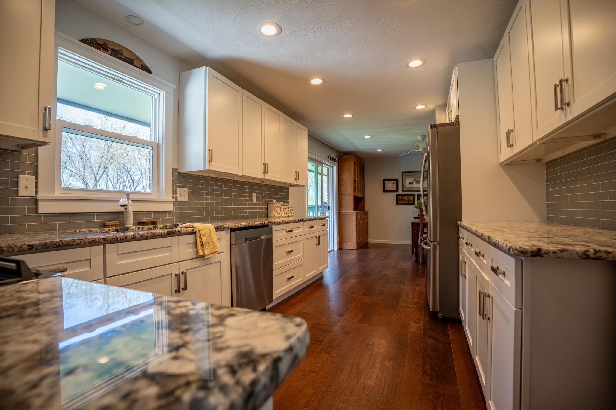 5968 East Bradley Road Byron, IL 61010 - Photo 13 of 40 a kitchen with stainless steel appliances granite countertop a refrigerator a sink dishwasher a stove and white countertops with wooden floor