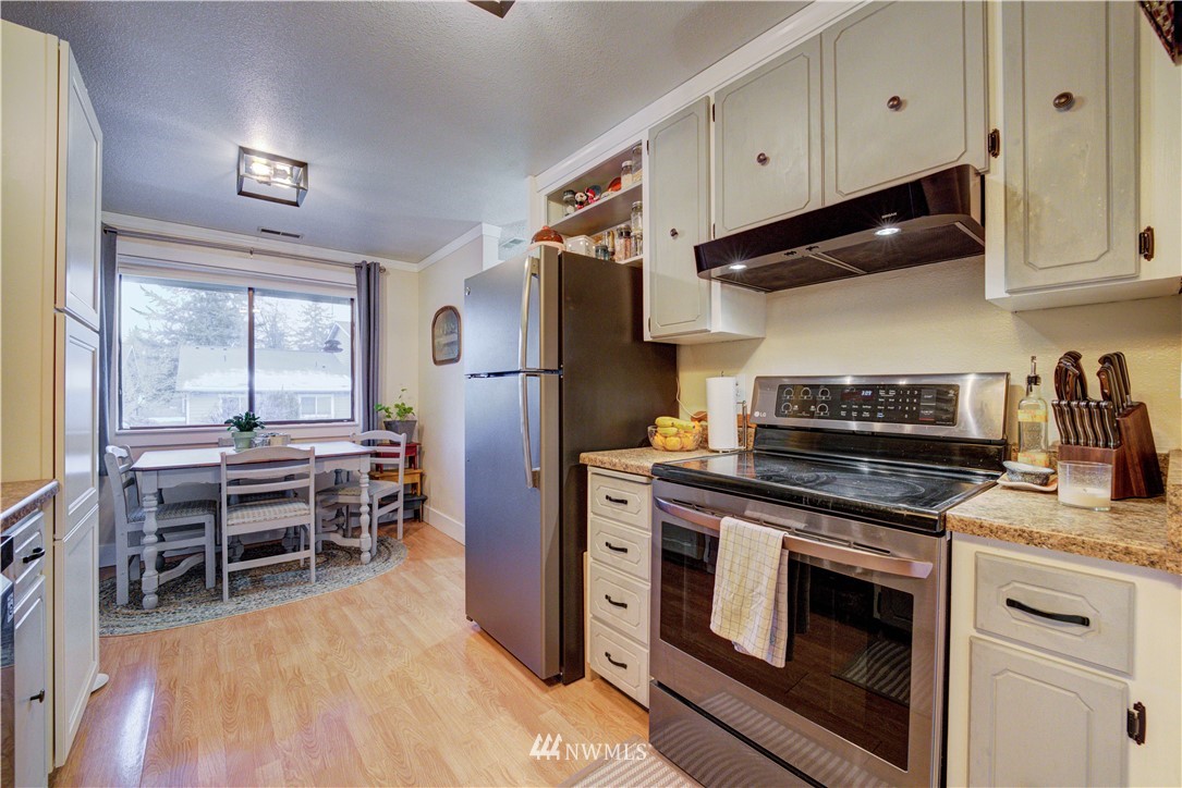 21515 4th Avenue West, Unit A72 Bothell, WA 98021 - Photo 13 of 36 a kitchen with stainless steel appliances a stove a refrigerator and wooden cabinets