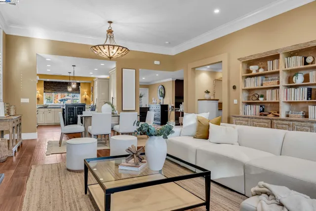 a living room with furniture kitchen view and a chandelier