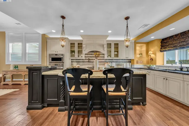 a kitchen with granite countertop a table chairs stove microwave and cabinets