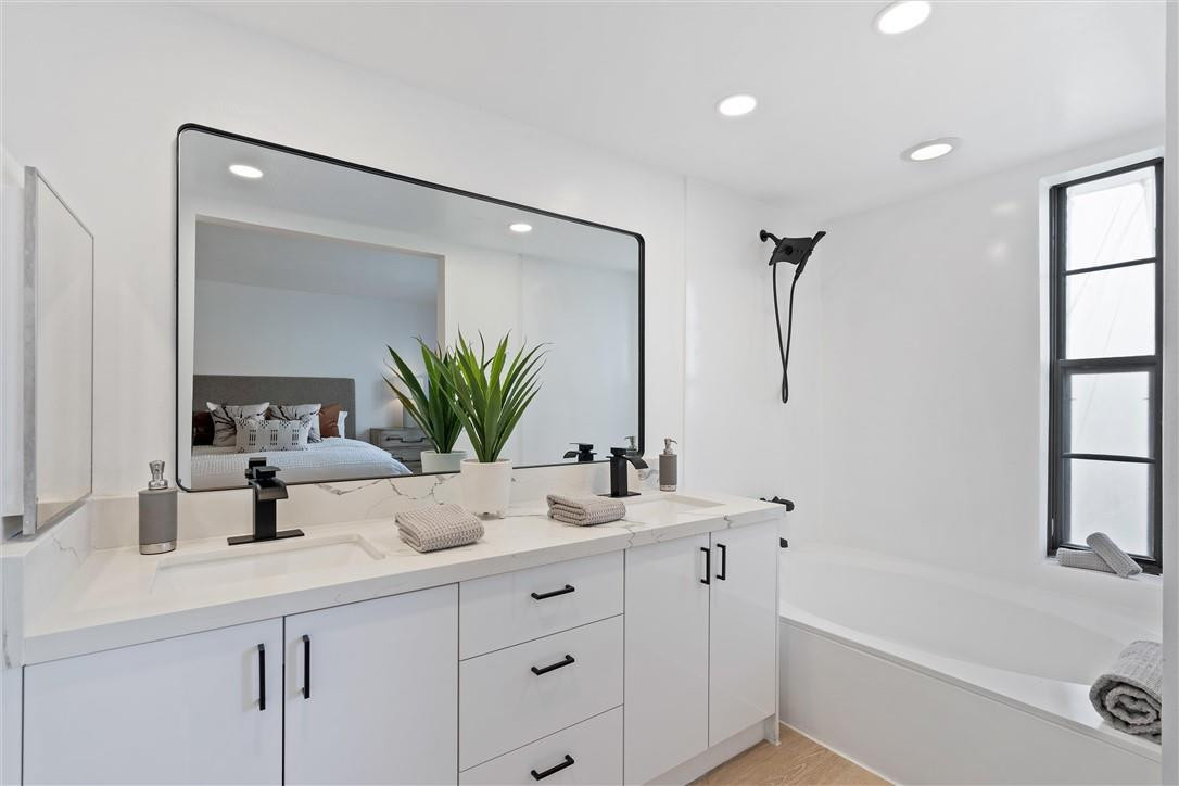 9233 Southwest 8th Street, Unit 108 Boca Raton, FL 33428 - Photo 8 of 9 a bathroom with a double vanity sink a mirror and a bathtub