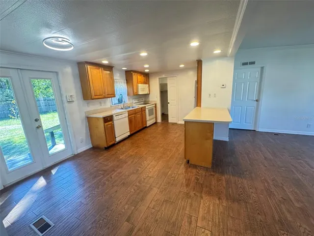 a kitchen with kitchen island wooden floors and stainless steel appliances