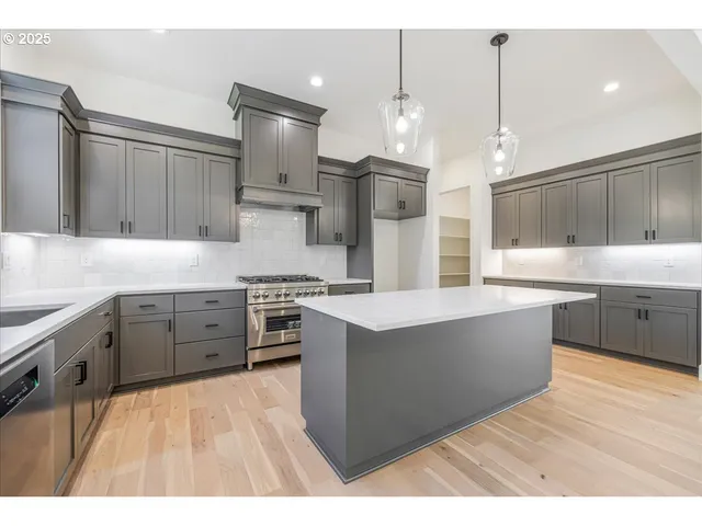 a large kitchen with stainless steel appliances kitchen island granite countertop a sink a stove and a refrigerator