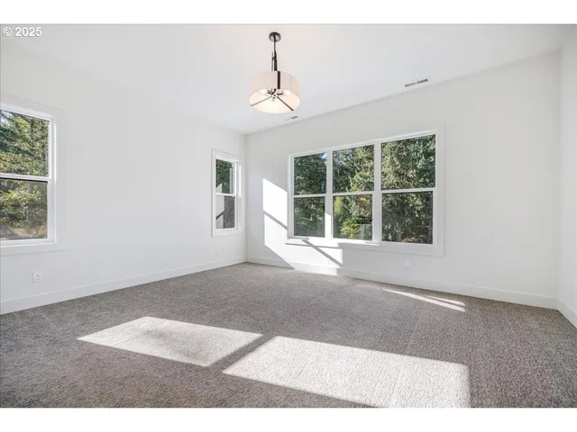 a view of an empty room with wooden floor and windows