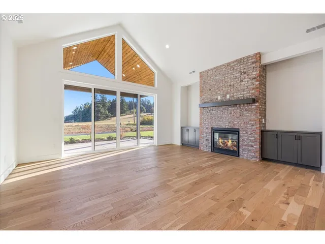 a view of an empty room with wooden floor and a fireplace