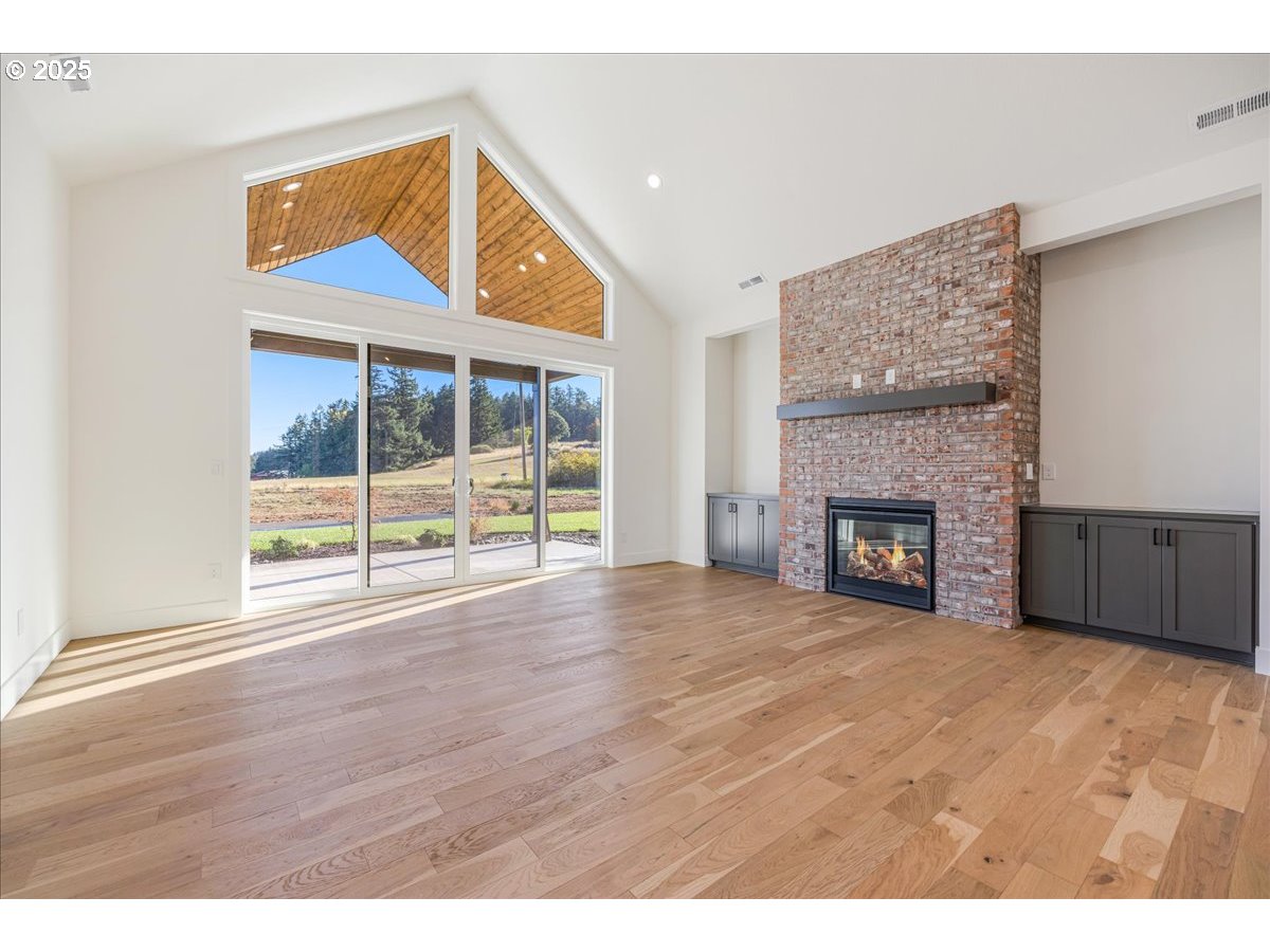7168 Southeast Eola Hills Road Amity, OR 97101 - Photo 6 of 34 a view of an empty room with wooden floor and a fireplace