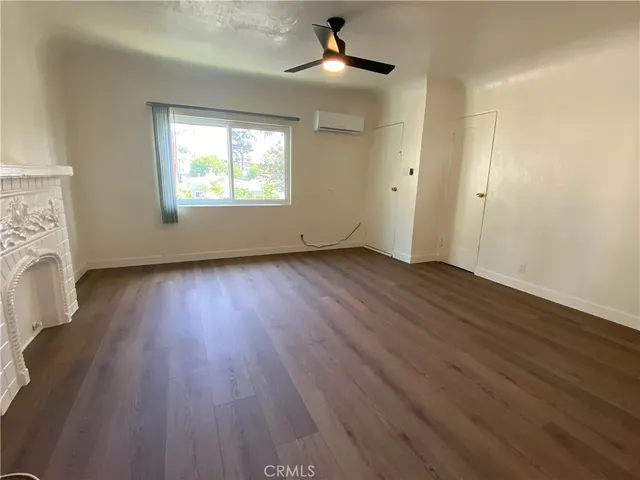 an empty room with wooden floor chandelier fan and windows