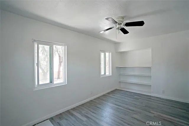 a view of an empty room with a window and wooden floor