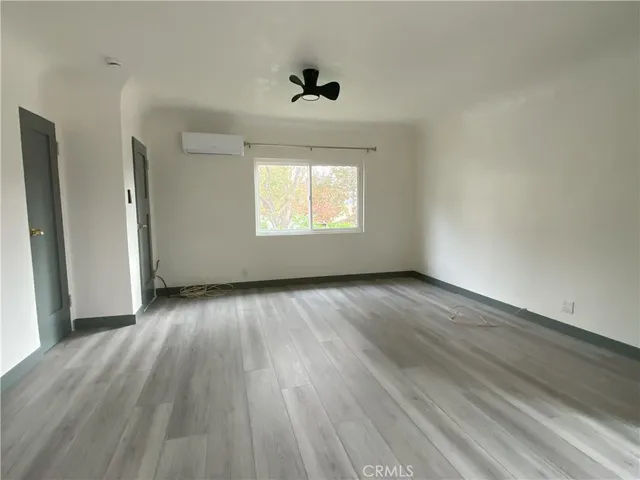 an empty room with wooden floor chandelier fan and windows
