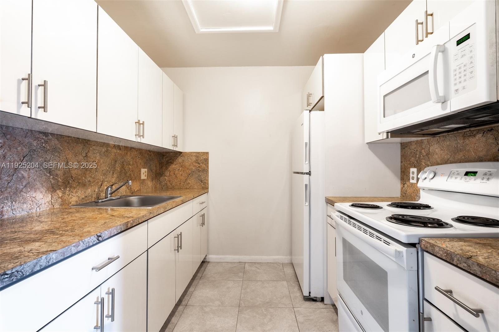 100 Southwest 132nd Way, Unit 306K Pembroke Pines, FL 33027 - Photo 9 of 31 a kitchen with granite countertop cabinets and white appliances