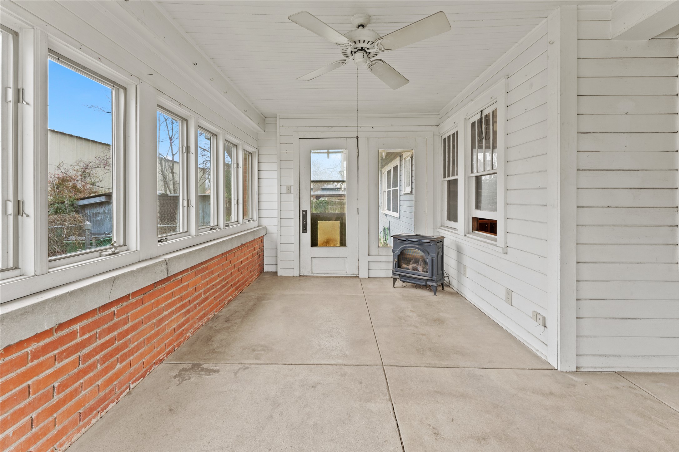501 East 6th Street Cameron, TX 76520 - Photo 10 of 39 Unfurnished sunroom featuring a wood stove and ceiling fan
