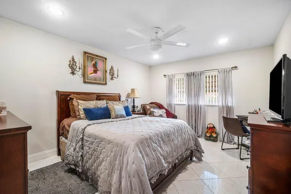 a bedroom with bed a flat tv screen and a dresser