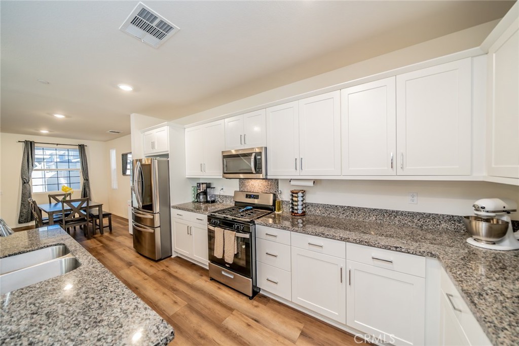 1810 Parkplace Lane Riverside, CA 92501 - Photo 11 of 52 a kitchen with stainless steel appliances granite countertop a stove a sink a refrigerator white cabinets and couches with wooden floor