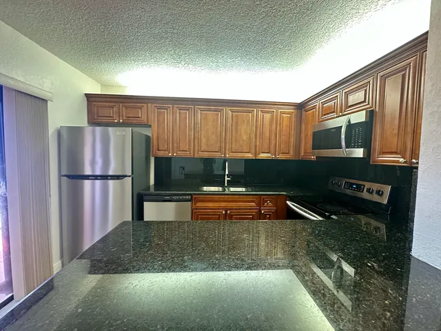 a kitchen with granite countertop a refrigerator and a sink