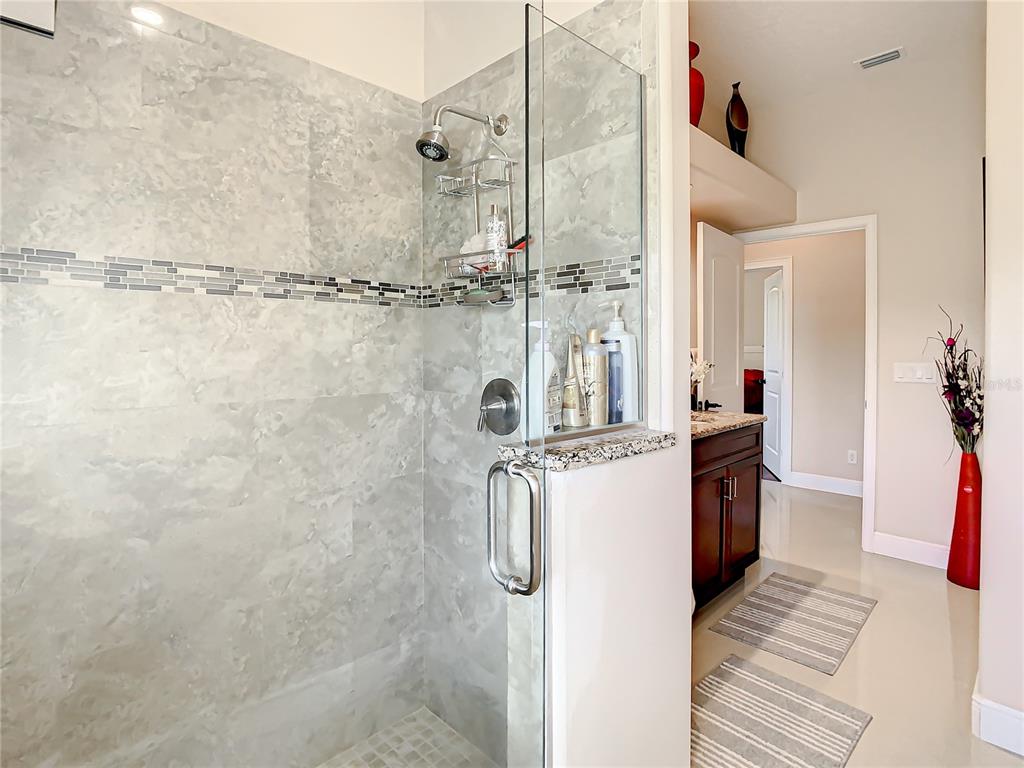 16300 Johns Lake Road Clermont, FL 34711 - Photo 46 of 76 a bathroom with a granite countertop shower a sink and a mirror