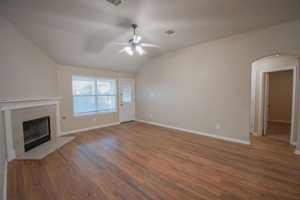 312 Pheasant Ridge Drive Round Rock, TX 78665 - Photo 5 of 34 A welcoming living space features warm wood flooring, a corner fireplace, and a door leading to outdoor access.