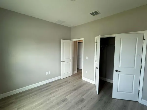 an empty room with wooden floor & closet area