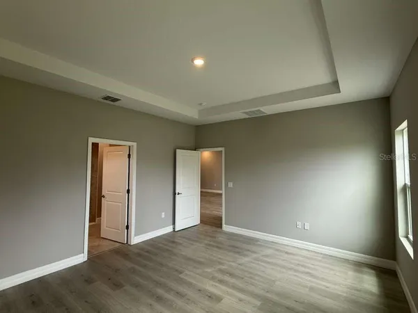 a view of an empty room with wooden floor and closet