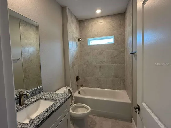 a bathroom with a granite countertop sink mirror toilet and bathtub