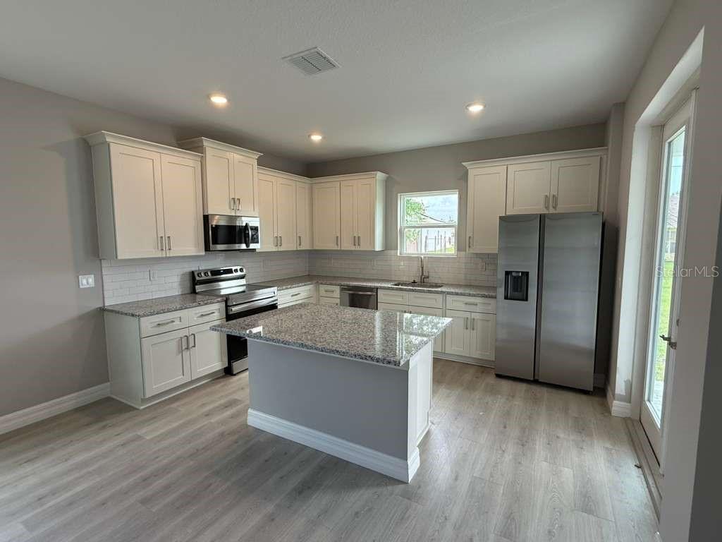 438 Awin Circle Southeast Palm Bay, FL 32909 - Photo 4 of 26 a kitchen with stainless steel appliances a refrigerator a stove a sink and white cabinets