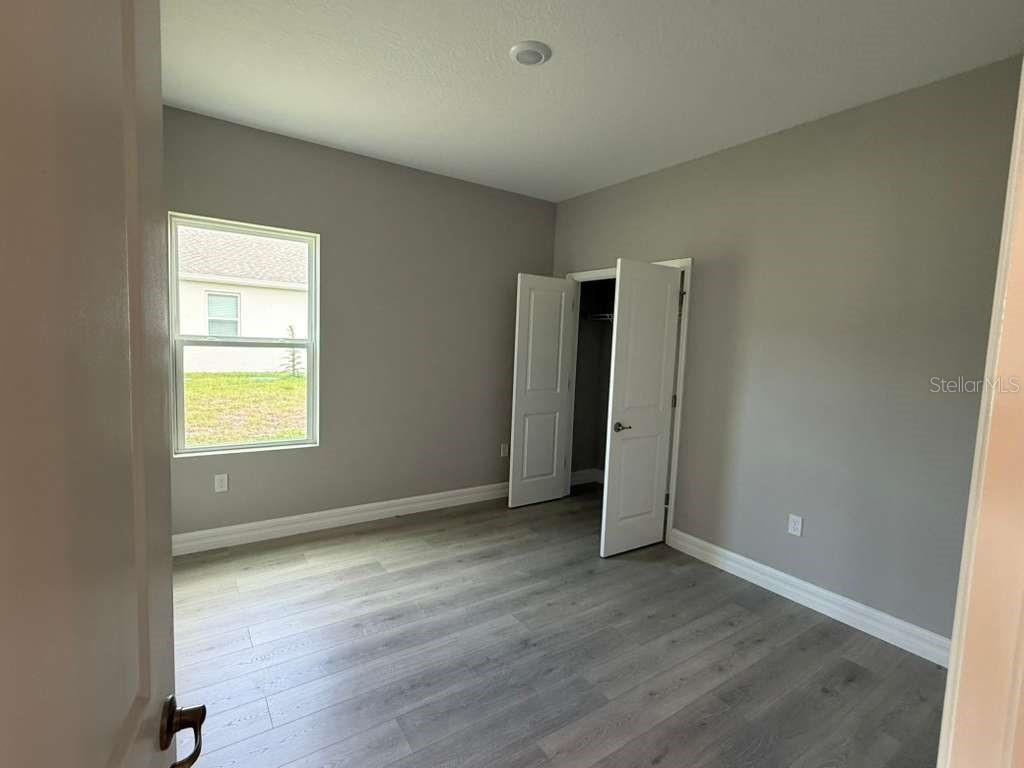 438 Awin Circle Southeast Palm Bay, FL 32909 - Photo 10 of 26 an empty room with wooden floor and windows