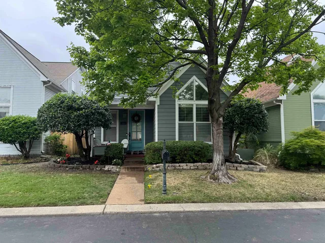 a front view of a house with a yard and potted plants