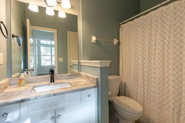 a bathroom with a granite countertop sink mirror vanity and toilet