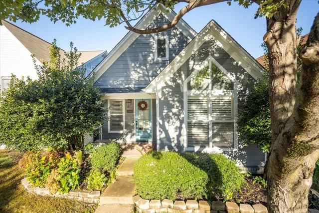 a view of a house with a large tree and flower plants