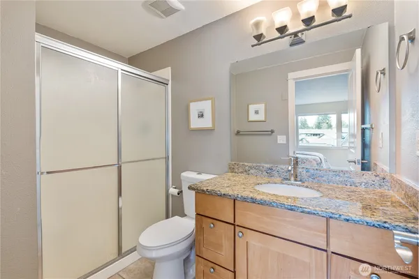 a bathroom with a granite countertop sink toilet and shower
