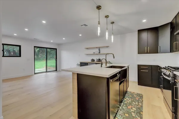 a large kitchen with stainless steel appliances kitchen island a large counter top a stove a refrigerator and a sink