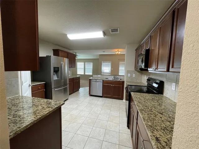 a kitchen with stainless steel appliances granite countertop a refrigerator a stove a sink and a microwave