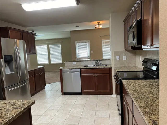 a kitchen with stainless steel appliances granite countertop a stove refrigerator sink and microwave