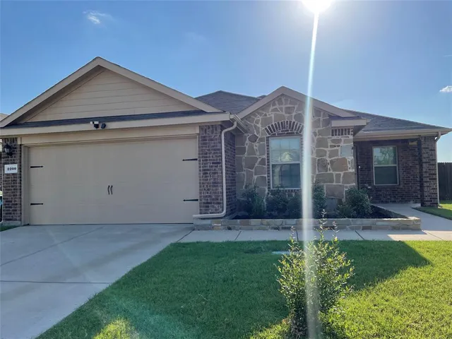 a view of a house with brick walls and a yard with plants