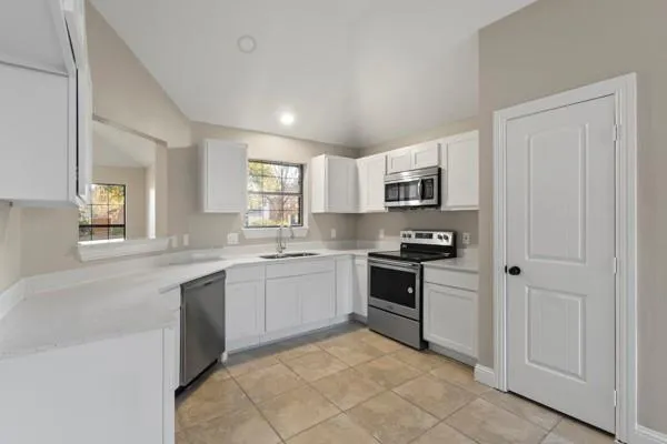 a large kitchen with cabinets stainless steel appliances and a window