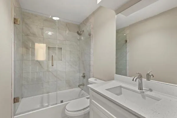 a bathroom with a bathtub shower sink vanity and toilet