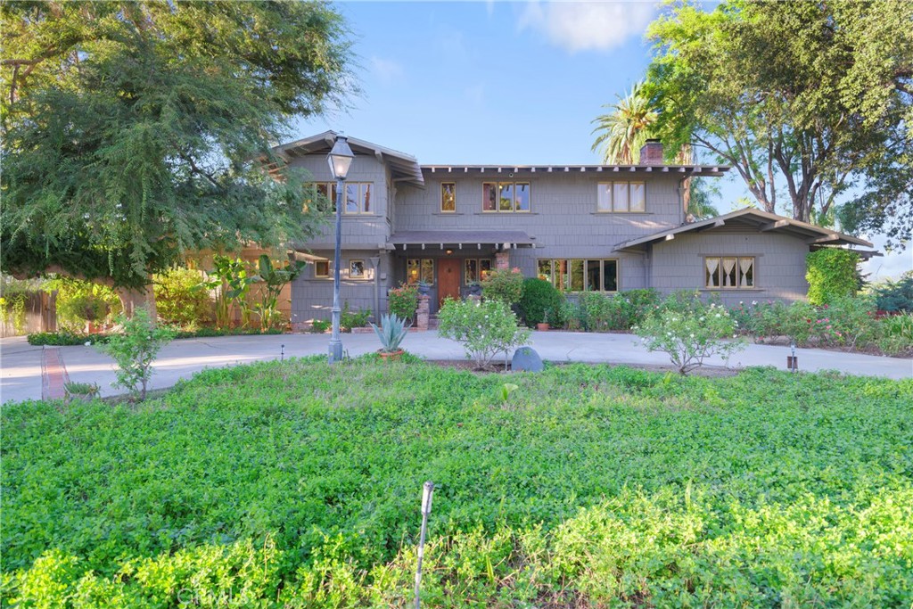 a view of a house next to a big yard and large trees
