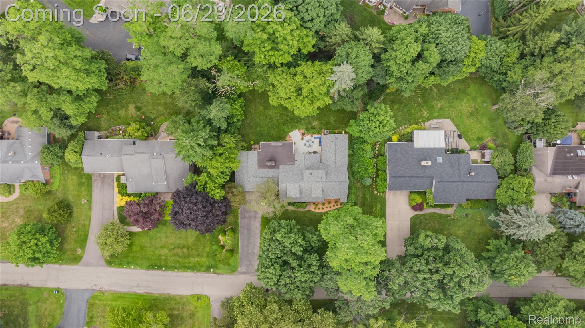 6085 Worlington Road Bloomfield Hills, MI 48301 - Photo 63 of 75 Aerial perspective showcasing a property surrounded by mature trees, featuring a dark shingle roof, a paved driveway, and extensive green lawn areas