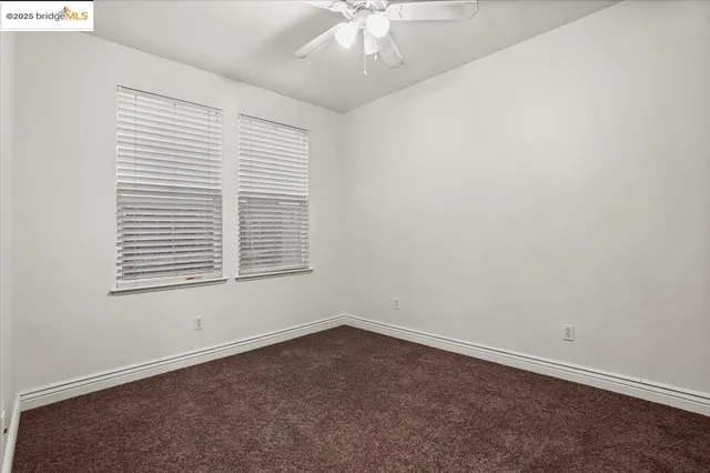 an empty room with a ceiling fan and window