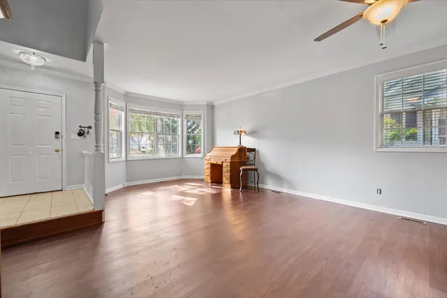 a view of empty room with wooden floor and fan