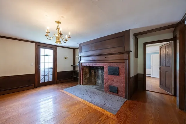 a view of a livingroom with a fireplace a chandelier and wooden floor